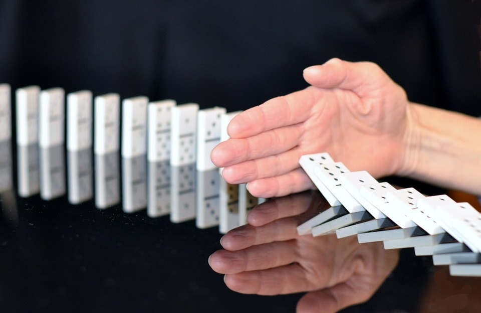 caída de fichas de dominó interrumpida por una mano